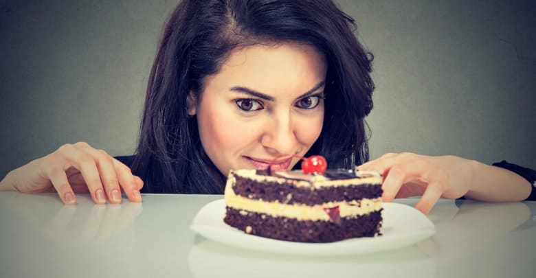 Woman craving cake dessert, eager to eat, isolated on gray background